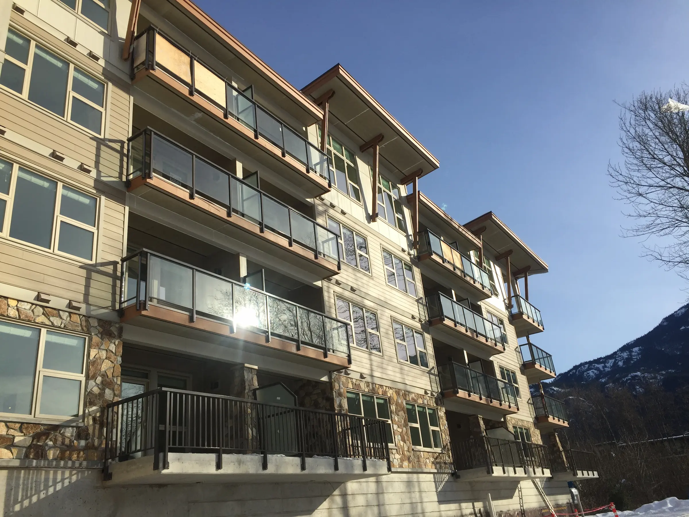 Modern apartment building with glass balconies under a clear blue sky.