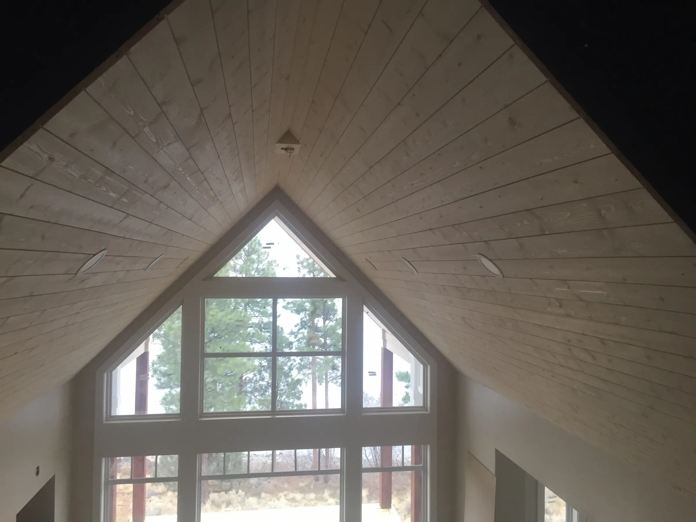 Interior view of a room with a high wooden vaulted ceiling and large triangular windows.